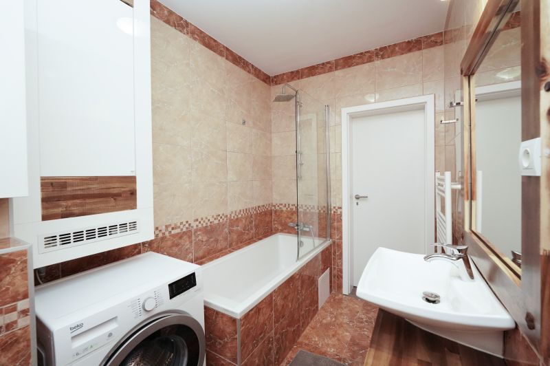 Bathroom with a bathtub, mirror, and washing machine, 3-room apartment; floor with wooden decor.
