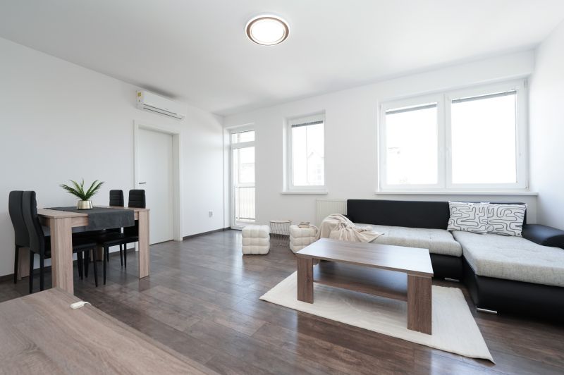 Bright living room with a sofa, dining table, and wood-patterned flooring.