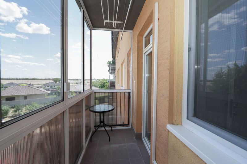 A glazed balcony with a view of rooftops and the sky, in a 3-room apartment.