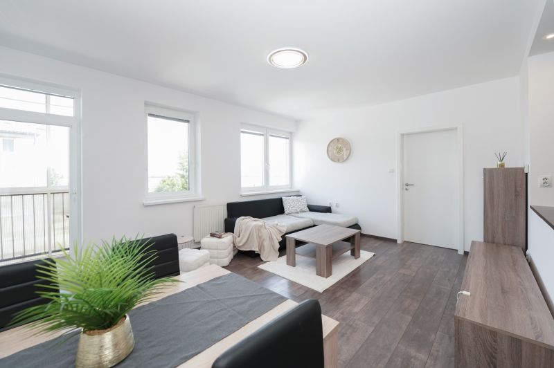 Living room in a 3-room apartment with wood-patterned flooring, large windows, sofa.