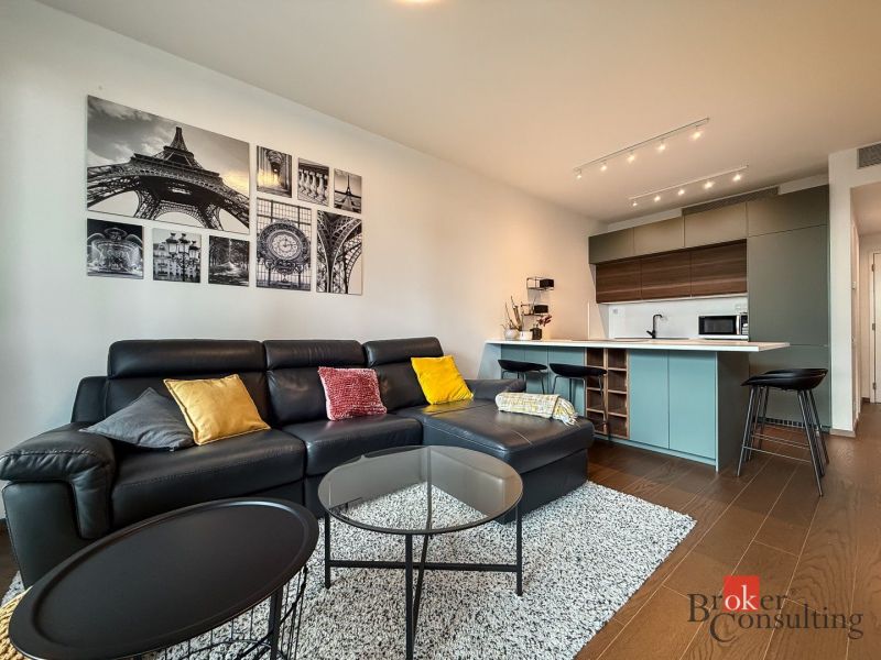 Living room with a leather sofa, pictures on the wall, and a wooden decor floor.