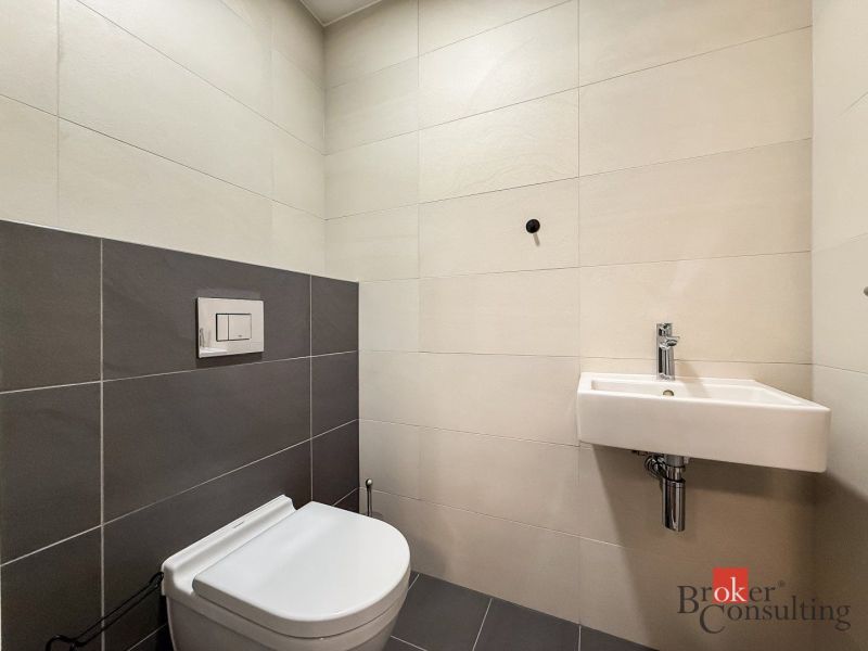 Bathroom with toilet and sink in a 2-room apartment with tiling.
