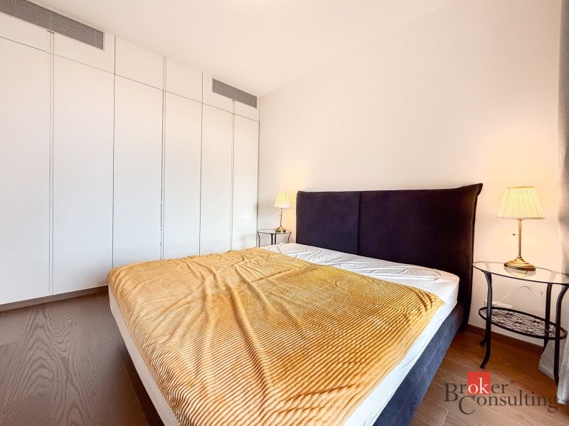 Bedroom in a 2-room apartment with a bed, nightstands, and a floor with a wood decor.