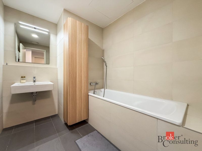 A bathroom with a bathtub and a sink in a 2-room apartment.