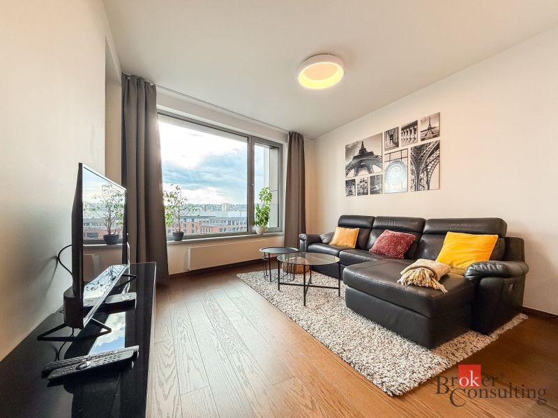 Living room in a two-room apartment with a leather sofa and a wooden decor floor.