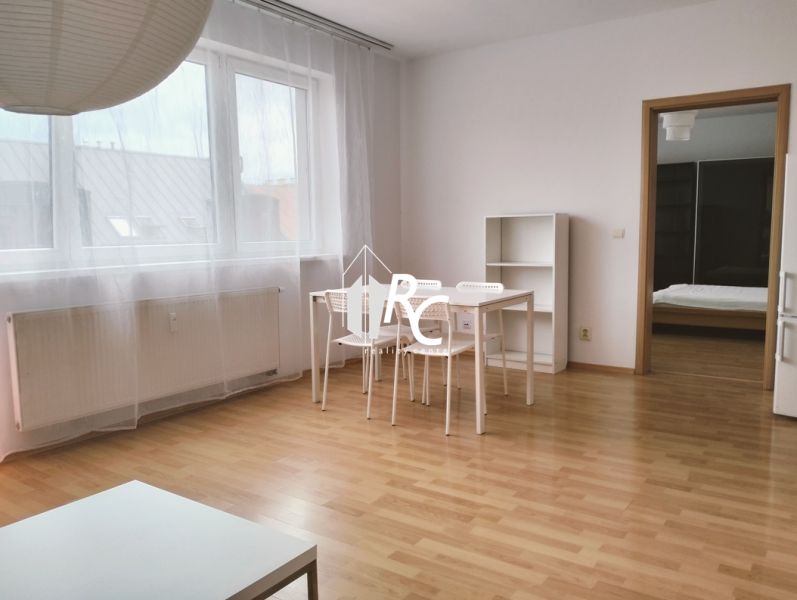 2-room apartment with wood-patterned flooring, white table with transparent curtains.