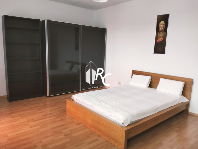 Bedroom in a 2-room apartment with a bed and a large wardrobe, wooden decor flooring.
