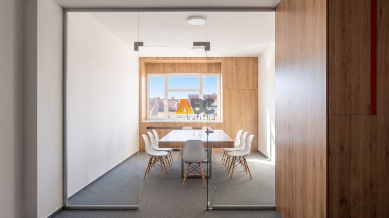Office with glass doors, wooden decor flooring, white desk and chairs.