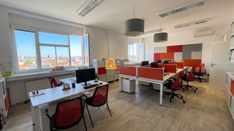 Offices with wood-patterned flooring and a view of the city through large windows.