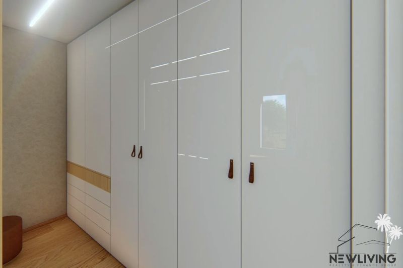 Built-in wardrobe with smooth white doors and brown handles in a 3-room apartment.