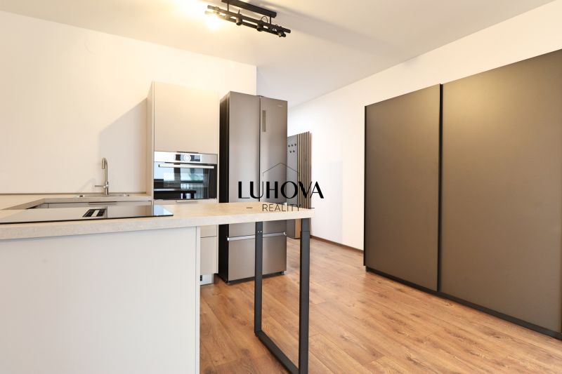 A kitchen in a studio apartment with a wood-patterned floor and built-in appliances.