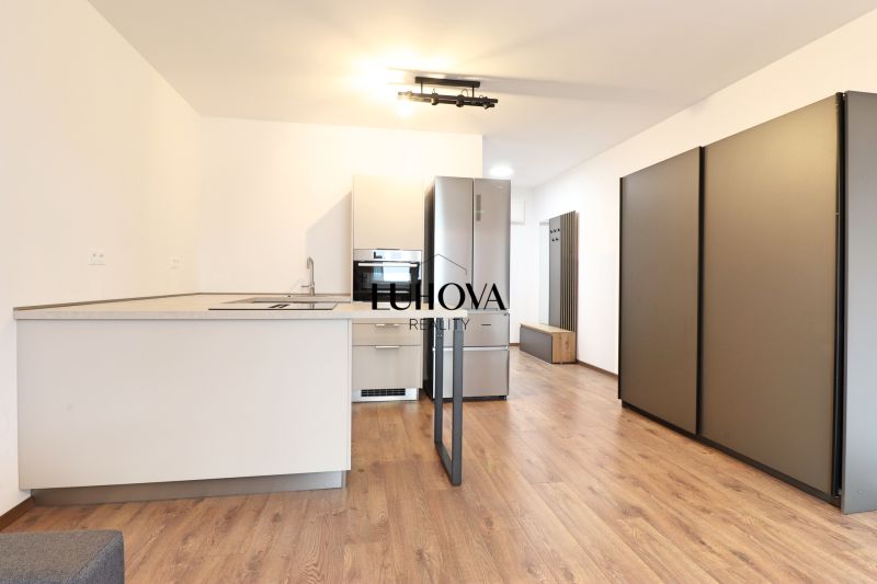 A kitchen in a studio apartment with a wood-patterned floor and modern lighting.