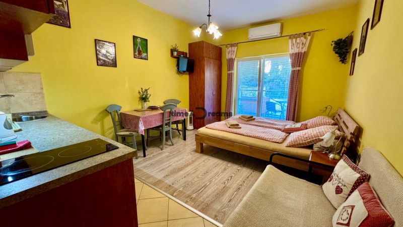 Interior of a holiday apartment with a wood-decorated floor, dining table, and bed.