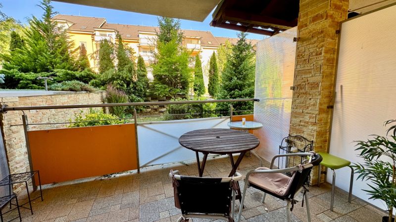 Balcony of a holiday apartment with a view of greenery and garden furniture in Podhájska.
