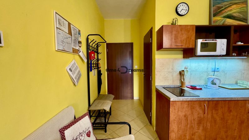 Interior of a vacation apartment with a kitchenette, microwave, coat rack, and wall decorations.
