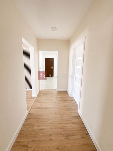 A hallway with a wooden decor floor in a 2-room apartment, white walls and interior doors.