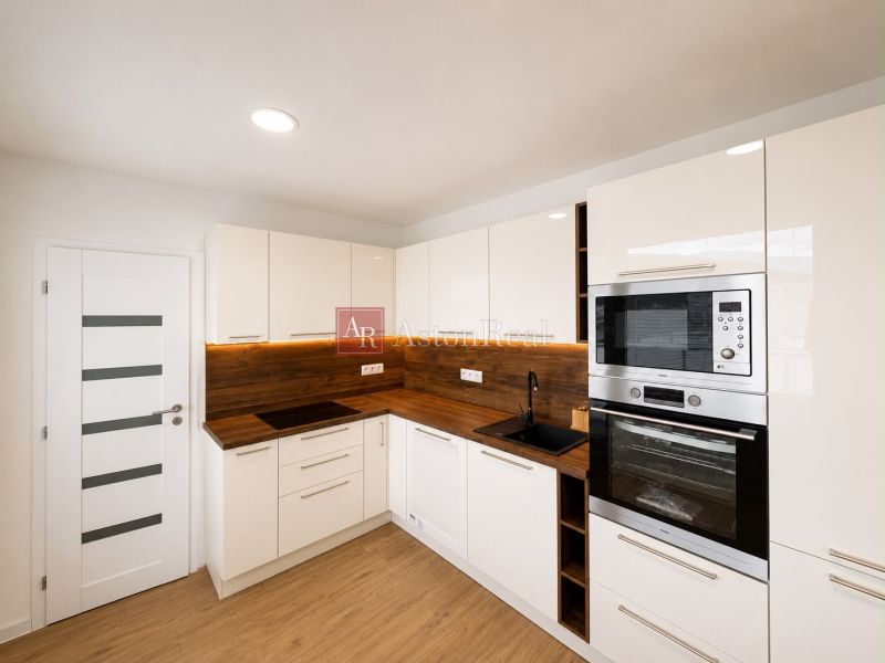Bright kitchen in a 2-room apartment with wood-patterned flooring and built-in appliances.