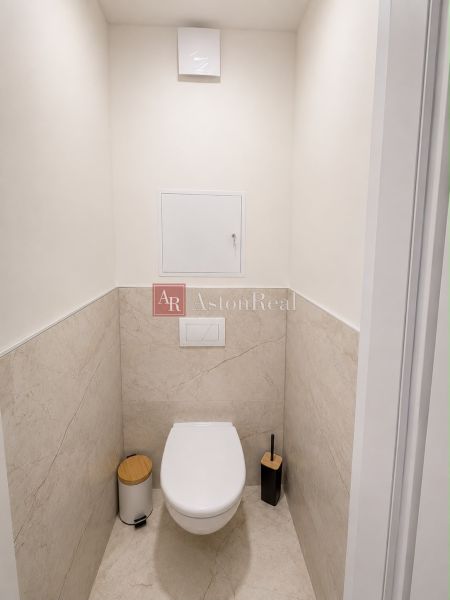 A bathroom with a simple design in a two-room apartment with beige tiles.