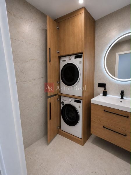Stylish bathroom in a 2-room apartment with a washing machine and dryer in wooden decor.