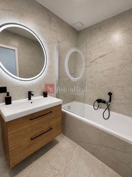 Bathroom in a 2-room apartment with a shower and furniture in wood decor.