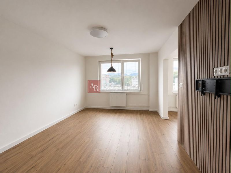 A room with a wooden decor floor and large windows in a 2-room apartment.