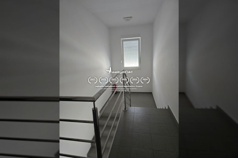 A staircase with a window in a 2-room apartment, dark flooring, and a steel railing.