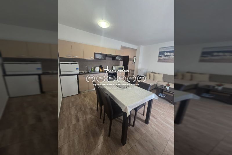 The kitchen of a two-room apartment with a corner sofa and a floor with a wooden decor.