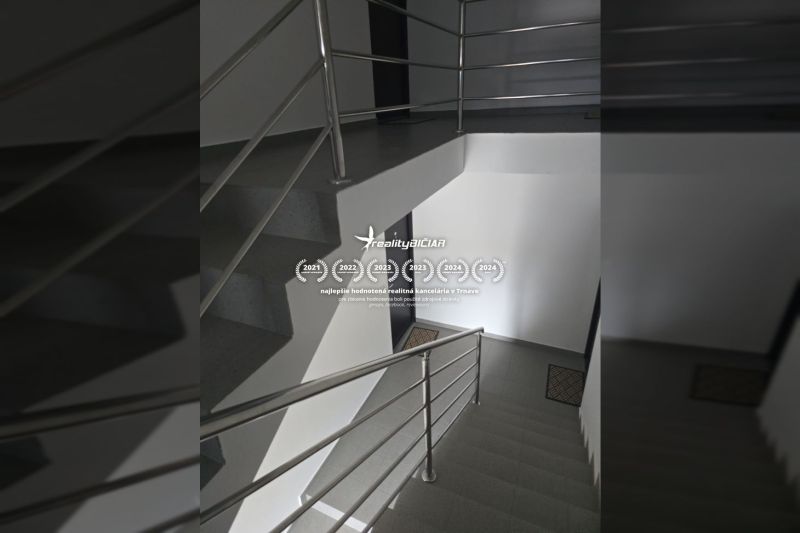 The interior of a staircase with a metal railing and gray flooring in a 2-room apartment.
