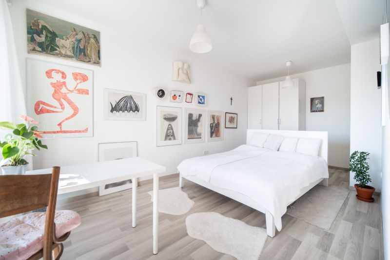 Bedroom of a two-room apartment with art on the walls and a floor with a wooden decor.