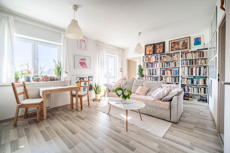Living room in a two-room apartment with a wooden decor floor, a bookshelf, and a sofa.