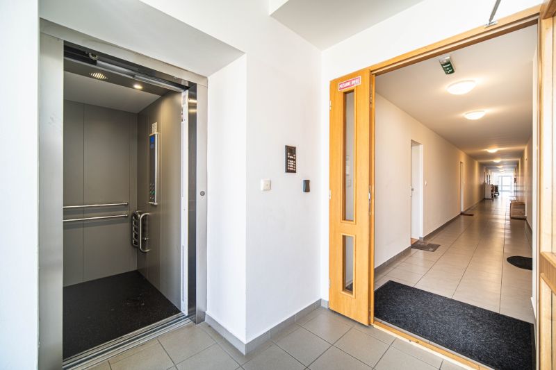 A hallway with an elevator in a 2-room apartment, neutral decor and clean lines.