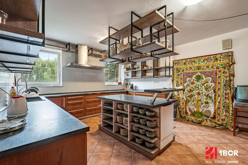 A kitchen in a family house with a ceramic floor and a colorful curtain.