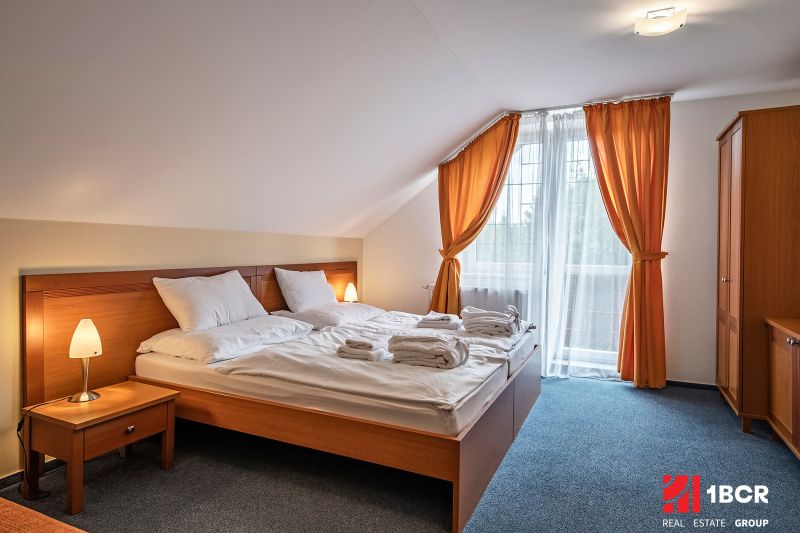 A bedroom with a double bed, orange curtains, and a table in a family house.