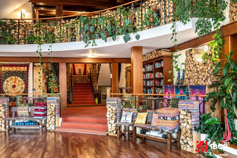 Interior of a family house with decorative trees, wooden-patterned flooring, and colorful cushions.