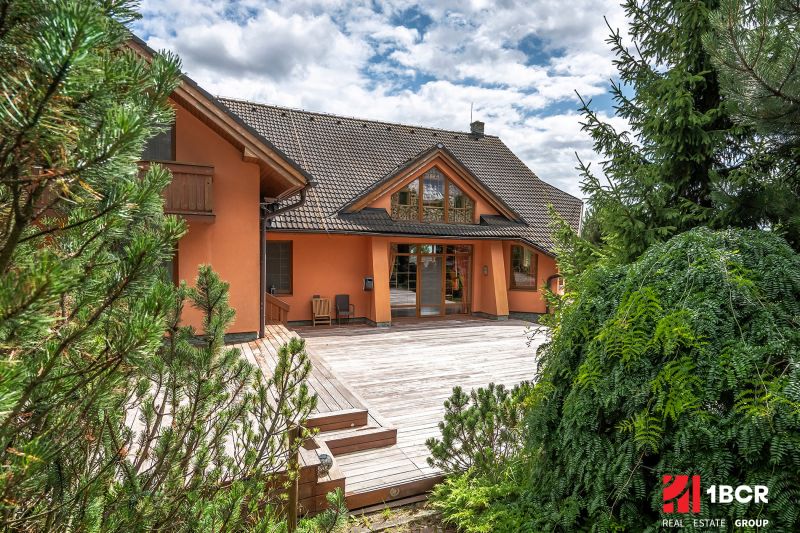 A family house in Veľká Lomnica with a garden and a wooden terrace surrounded by coniferous trees.