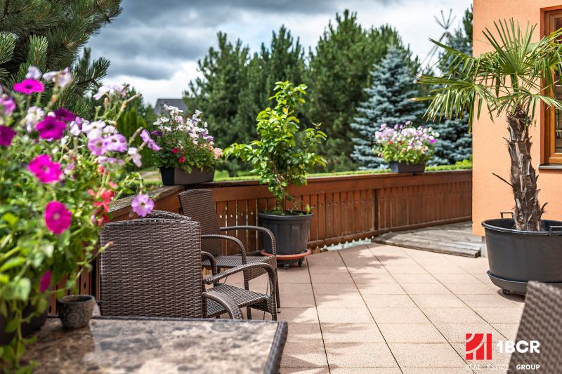 The exterior of a family house in Veľká Lomnica with a terrace surrounded by flowers and plants.