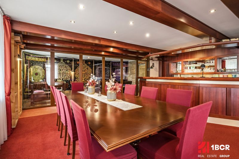 A dining room in a family house with wooden elements and red chairs at the table.