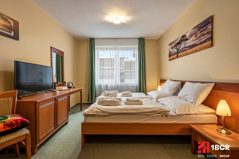 A bedroom with two beds, a television, and a painting in a family house.