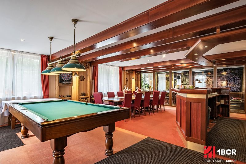Interior of a family house with a billiard table, wooden decor, and a dining table.