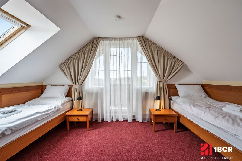 A room in a family house with two beds, a red carpet, and a skylight.