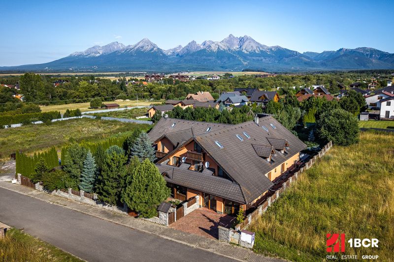 A family house in Veľká Lomnica, surrounded by mountains, in the middle of a green landscape.