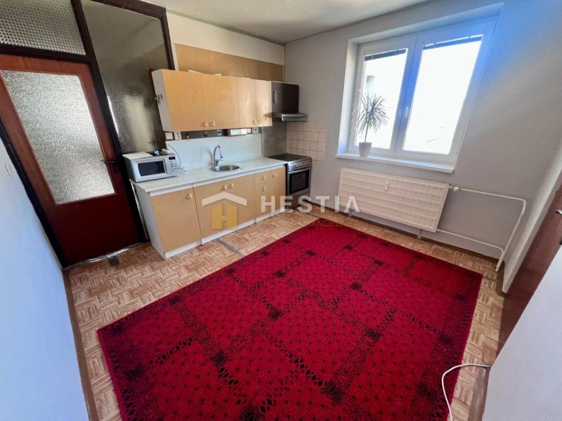 A kitchen with a carpet, a wooden decor floor, and a microwave in a 3-room apartment.