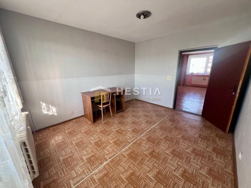 A room with a wooden floor decor, a desk, and a chair in a three-room apartment.