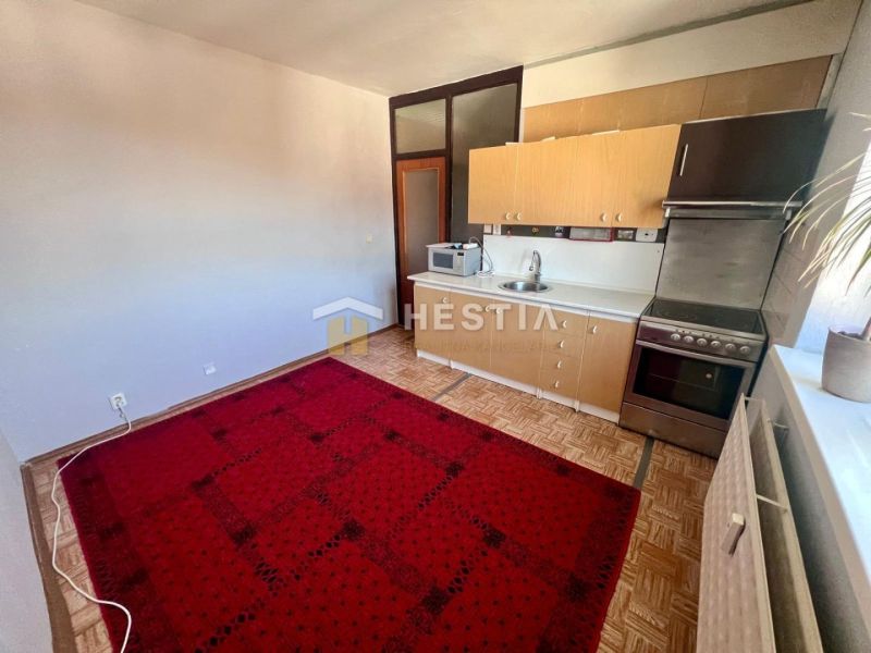 A kitchen with a wooden decor floor and a red carpet in a 3-room apartment.
