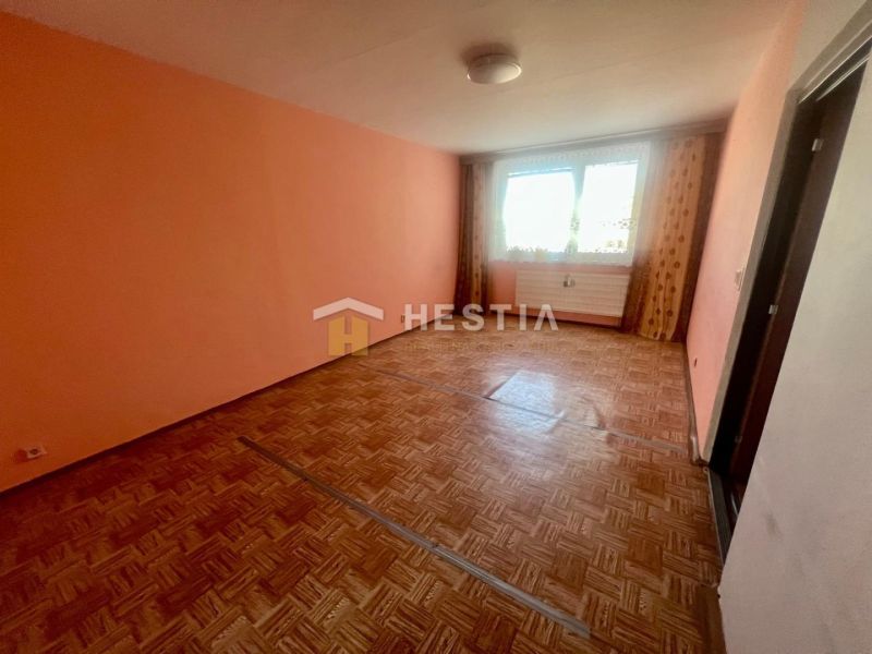 A room in a 3-room apartment with orange walls and a wooden decor floor.