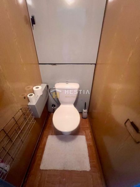A toilet with light walls and a wooden decor floor in a 3-room apartment.