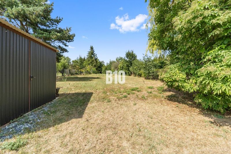 A garden at a family house in Podhájska with a lawn and a wooden shelter.