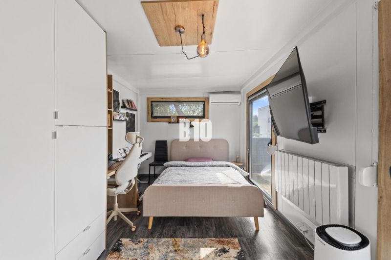 Bedroom with a bed and a table in a family house with a wooden decor floor.