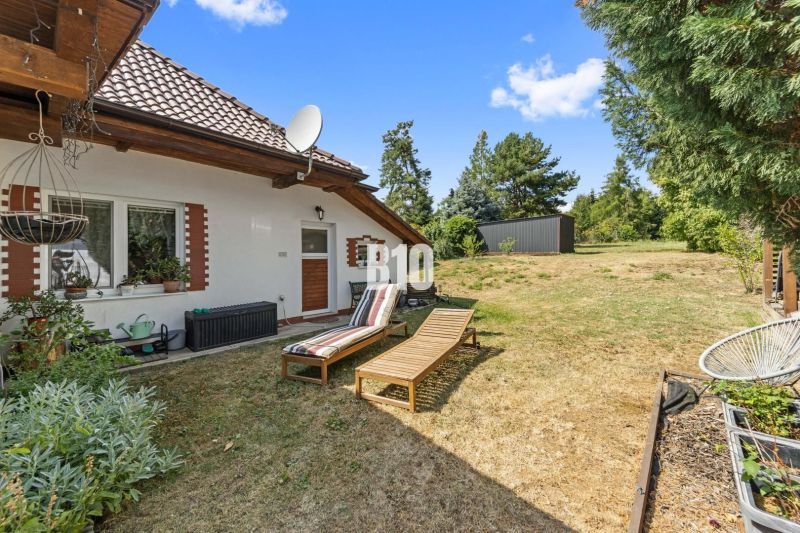 A family house in Podhájska with a terrace, sun loungers, and a satellite dish on a grassy plot.