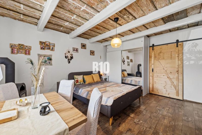 Interior of a family house with a bed, dining table, and decorative wooden ceiling.